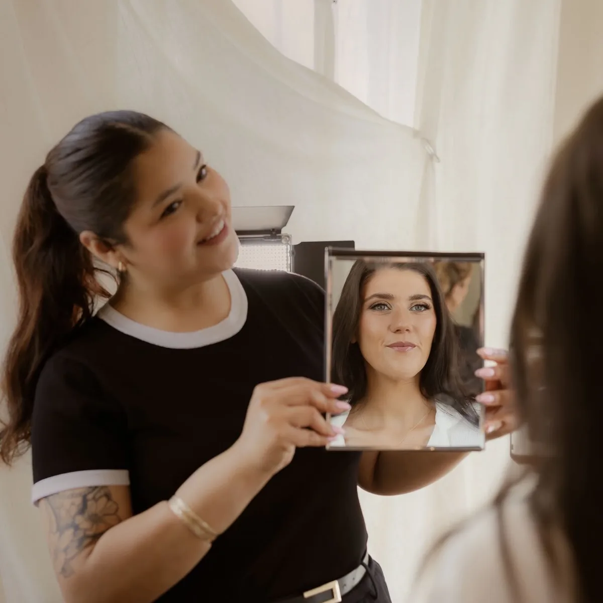 Eunice holding the mirror as a bride sees her finished look