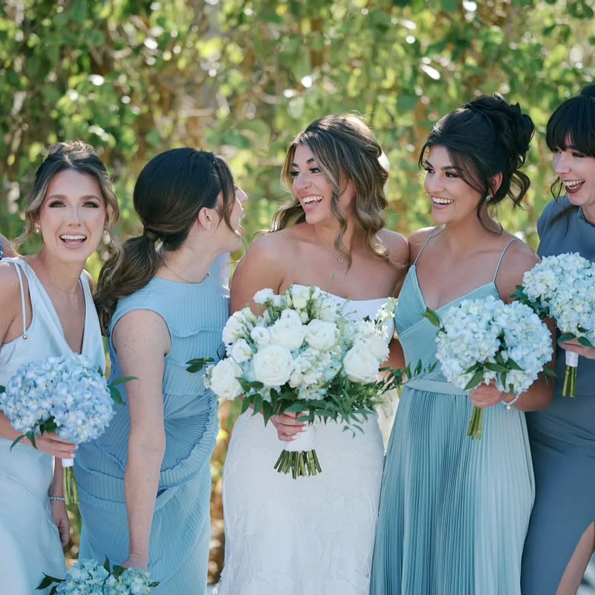 A bride laughing with her bridesmaids, all glammed for the day
